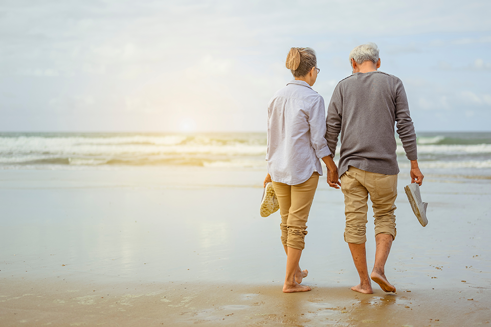 Happy older couple walking on the beach