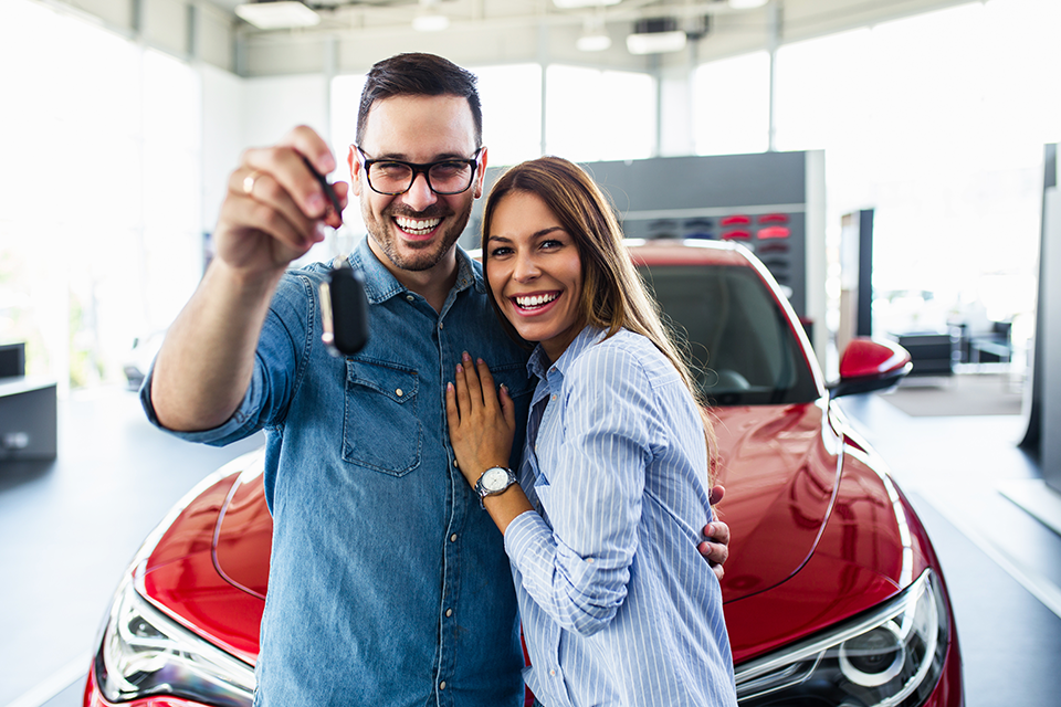 Man and woman, smiling and hugging in dealership