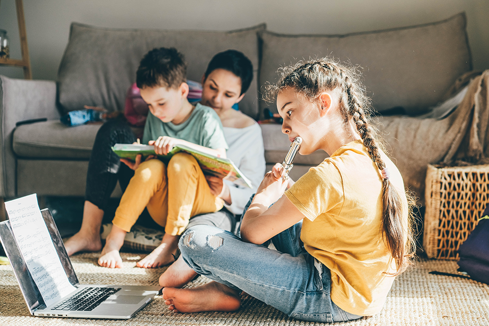 Mom helping her son with homework. Girl playing the flute at home.