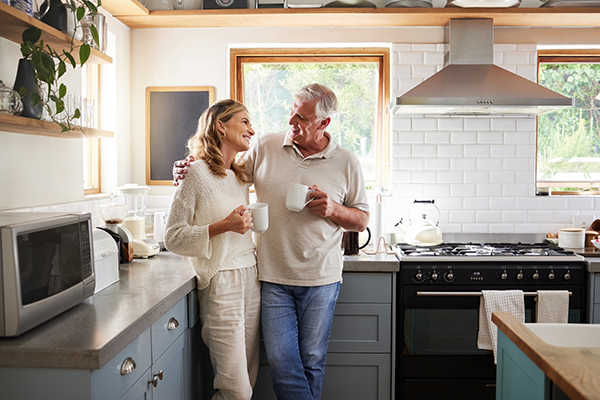 Mid-aged couple standing in kitchen drinking coffee