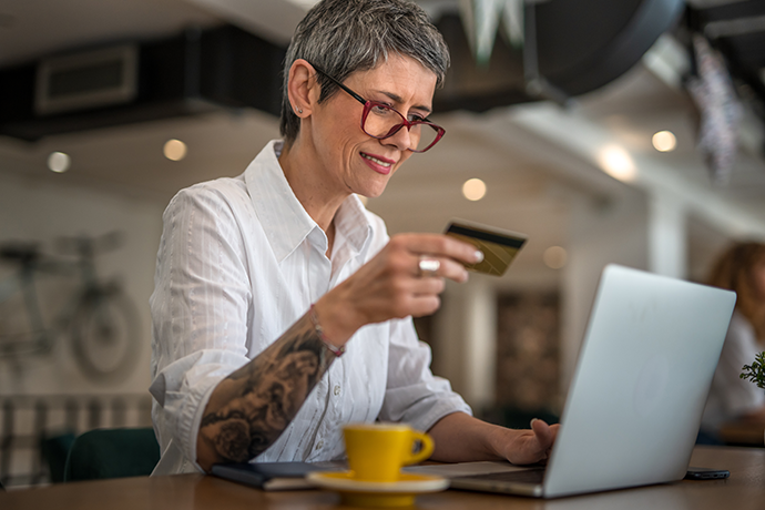 woman with eyeglasses holding credit card and shopping online on laptop