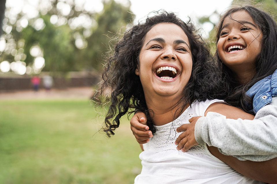 Smiling mother giving daughter piggyback ride.